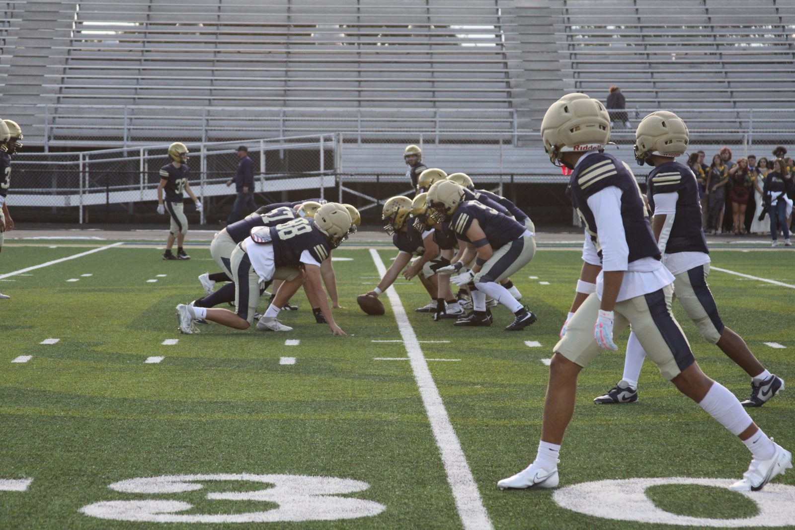 Columbian football players in navy and gold uniforms line up across from each other on the field.
