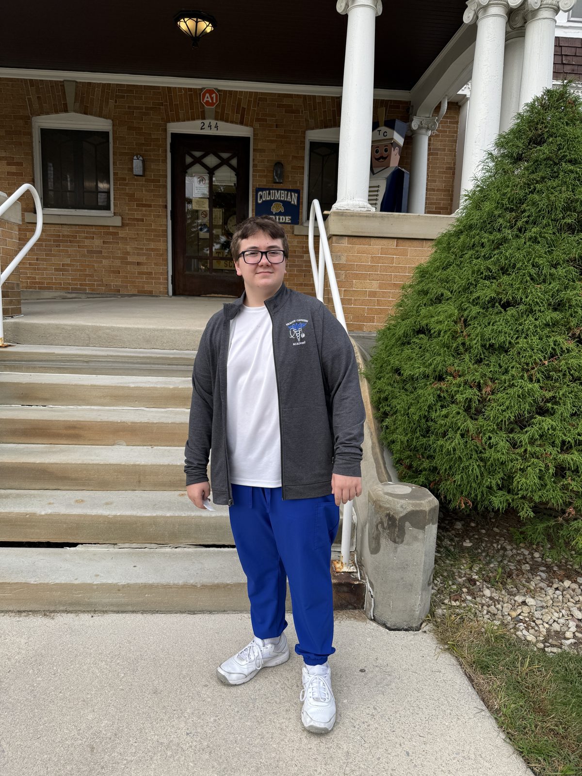 James Lovelace stands on a sidewalk beside the steps of a brick building.