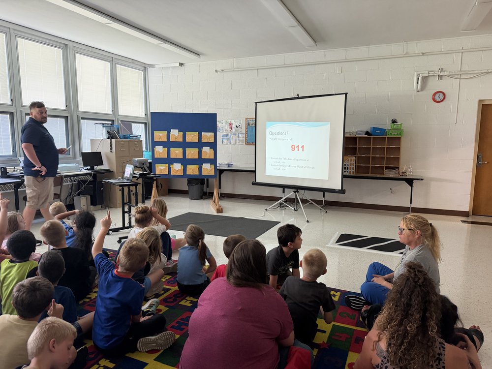 Students raise their hands during a Safety City classroom lesson on when and how to call 911.