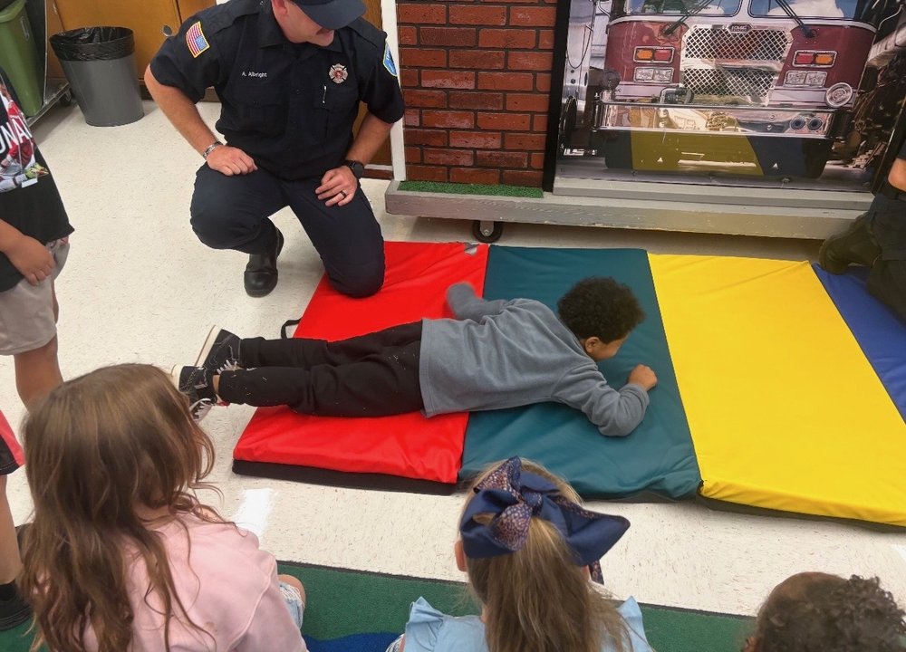 A Tiffin Fire Rescue Division firefighter guides a student through a hands-on fire safety drill.